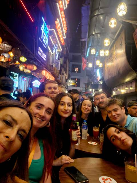       Group of friends enjoying nightlife on a busy street with neon signs.
  