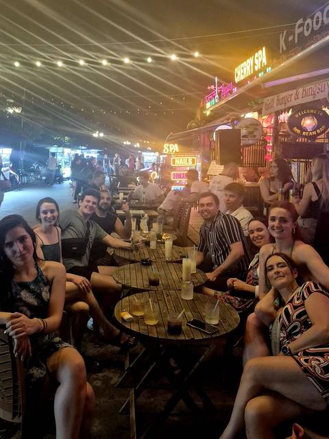       People sitting outside at a cafe in a bustling street.
  