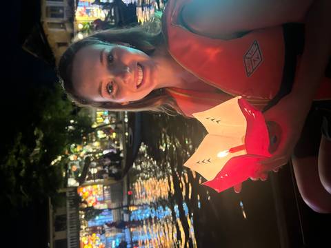       Person holding a floating lantern on a river during a festival.
  