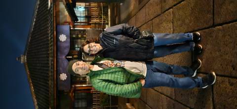 Two people posing in front of a building at night in Japan.