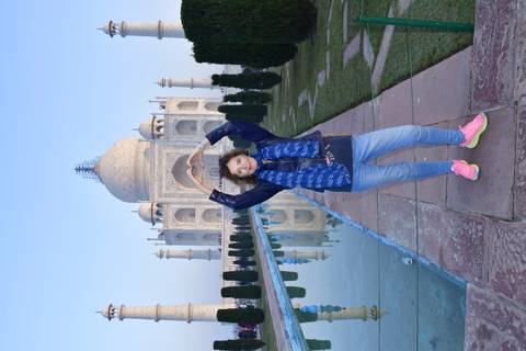       Tourist making heart gesture in front of the Taj Mahal.
  