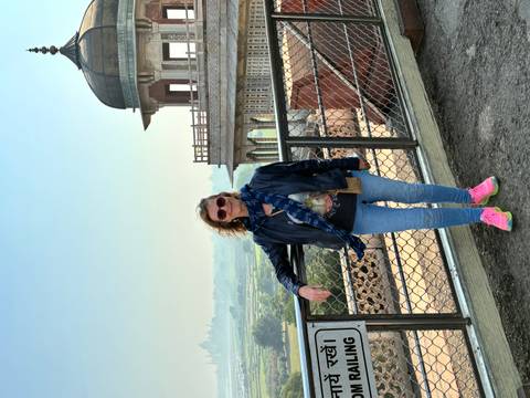       Woman posing at Fatehpur Sikri with scenic backdrop.
  
