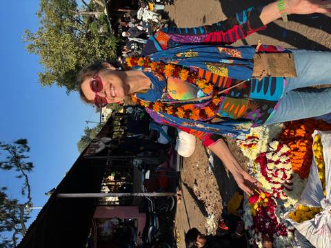      Woman surrounded by flower garlands at an open market.
  