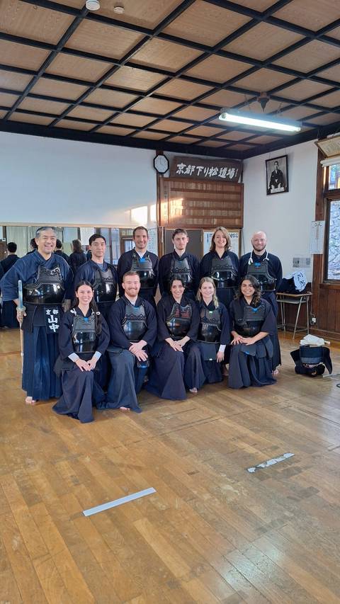 Group dressed in kendo uniforms posing inside a dojo.
