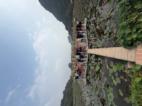 Large group of people standing on a bridge over a lotus pond.