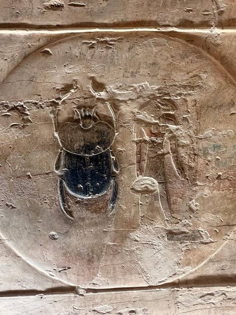 Ancient carvings on a stone wall depicting symbols.