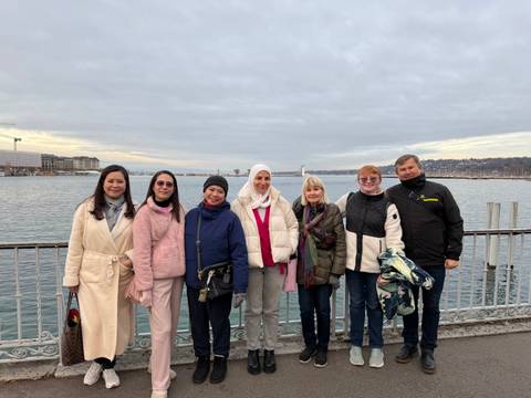       Group of tourists posing by a lake with cloudy skies.
  