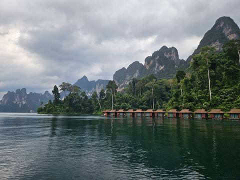       Floating bungalows on a lake surrounded by mountains.
  