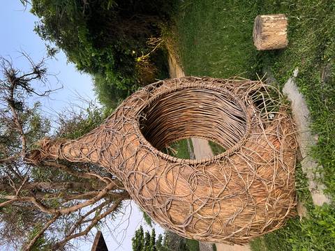       A woven wicker nest-like structure in a garden setting.
  