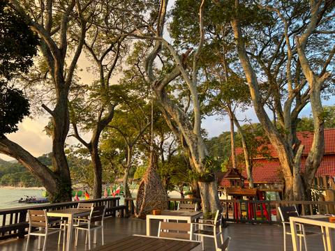       A terrace with seating in a lush garden setting by the sea.
  