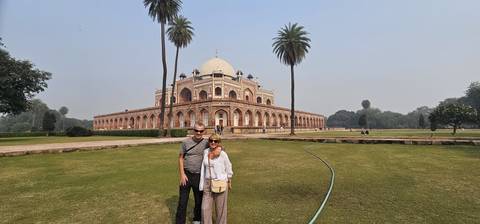Two people standing in front of a historic tomb building.