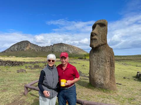 Two people posing next to a Moai statue.
