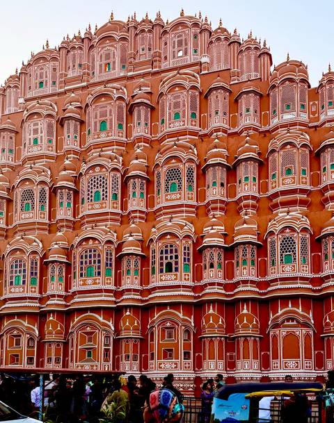       Close-up of the intricate windows of the Hawa Mahal, painted in pink and red.
  