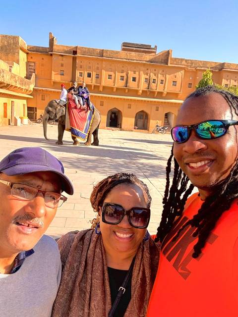 A group of people posing with an elephant in a courtyard.