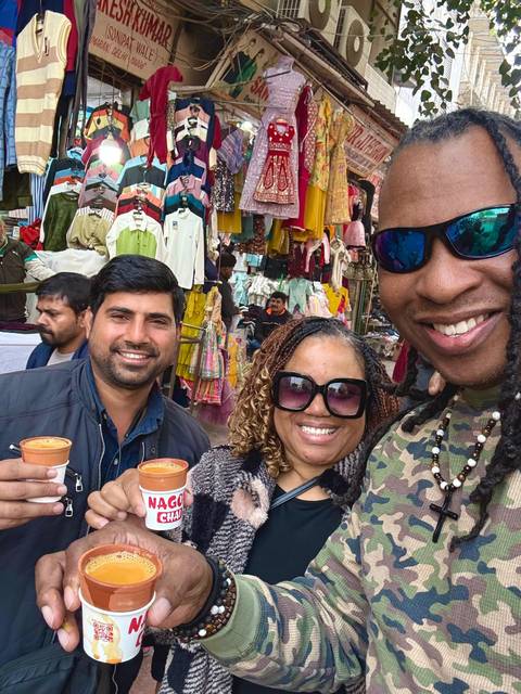       Four people enjoying tea in clay cups at a bustling market.
  