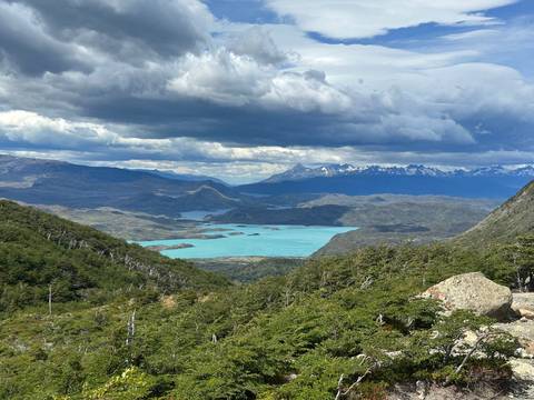       A vast landscape with mountains and a turquoise lake.
  