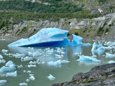       Icebergs floating in a lake against rocky mountains.
  