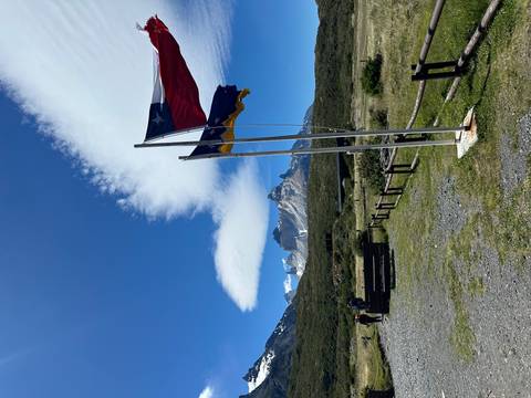       Flags with mountains in the background under blue sky.
  