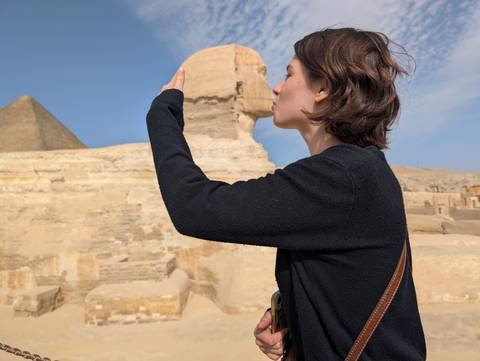 A person posing with a perspective trick to align with the Sphinx.