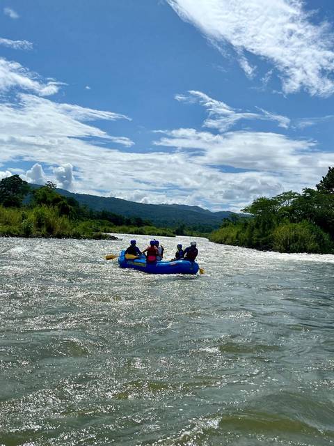 Group of people rafting down a river surrounded by forested mountains.