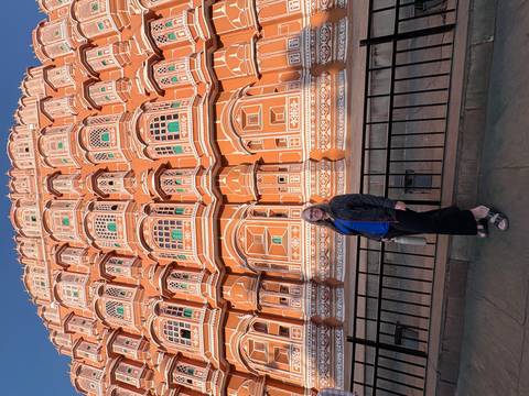 Individual standing in front of the Hawa Mahal, an iconic building in Jaipur.