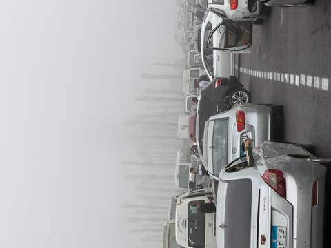 Heavy traffic with people on a foggy day.