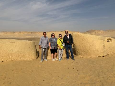       Group of people posing in front of sandstone formations in a desert landscape.
  