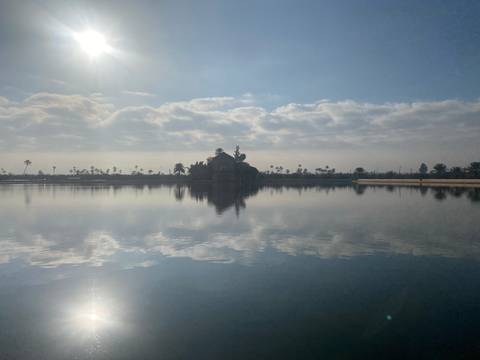 Reflections on a calm body of water with distant buildings