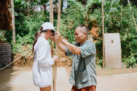       Person assisting with a bamboo pole in a traditional activity.
  