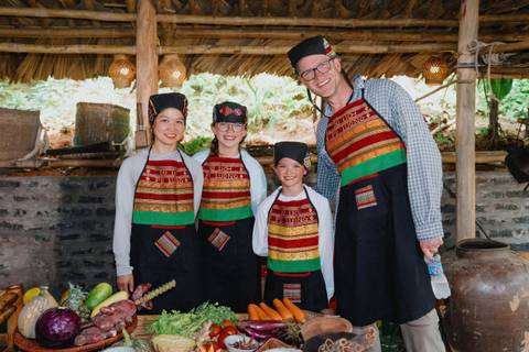       Family posing with traditional cooking attire and vegetables.
  