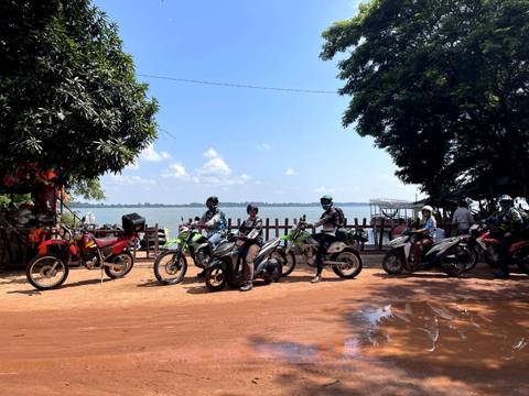      Group of people on motorbikes by a lakeside.
  