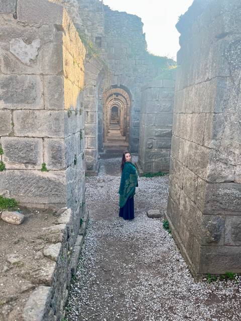 A person standing in an ancient ruin corridor.