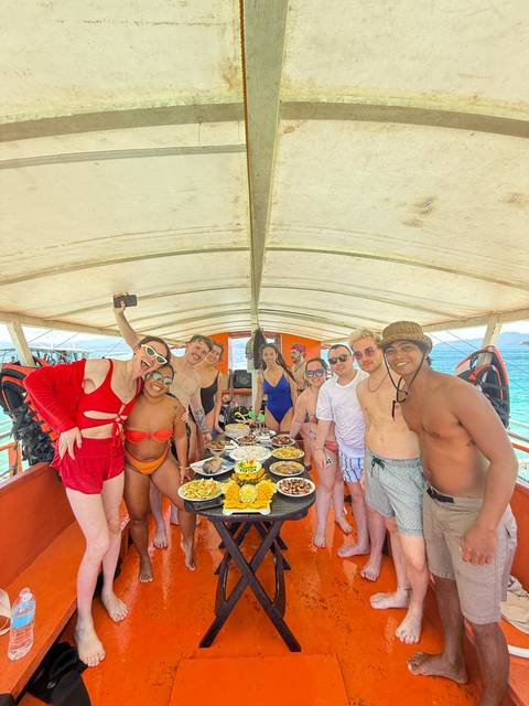 Group of people posing on a boat with a spread of food and life vests.
