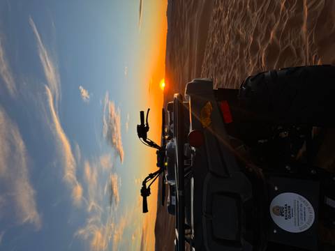 All-terrain vehicle in the desert at sunset.