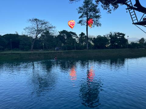       Hot air balloons over a river with reflections.
  