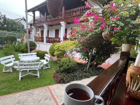       Garden with flowers and a white table set in front of a traditional building.
  