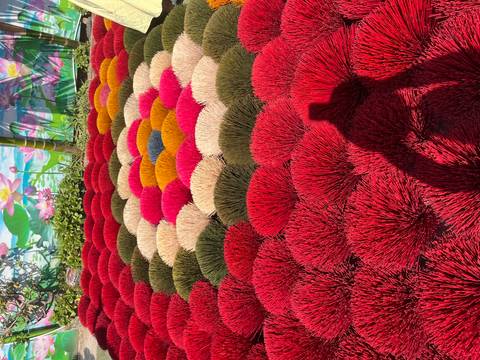      Colorful bundles of dried incense sticks arranged on the ground.
  