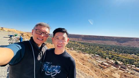 Two people taking a selfie with a scenic desert backdrop.