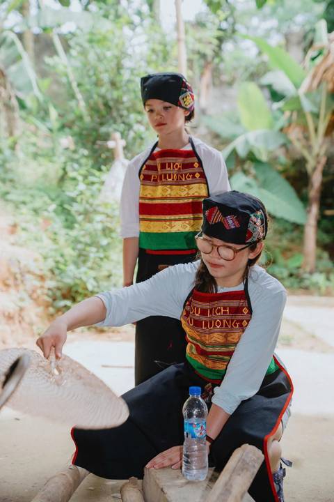       A person in traditional attire preparing food outdoors.
  