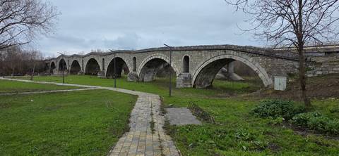       An old stone bridge with multiple arches on a cloudy day.
  