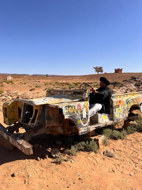 Man driving a vintage vehicle in a desert landscape.