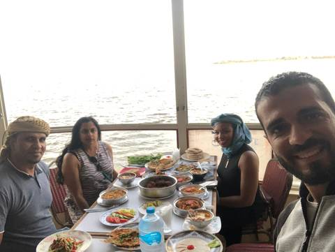       Group of people enjoying a meal by the water.
  