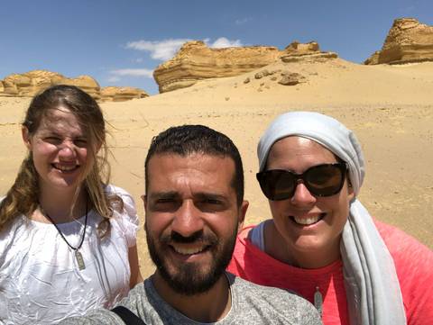       Group of people in a desert with rock formations.
  