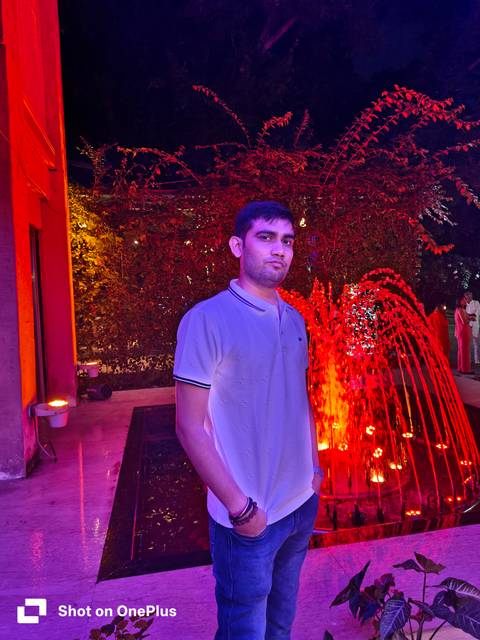       Person standing beside a lit fountain in the evening.
  