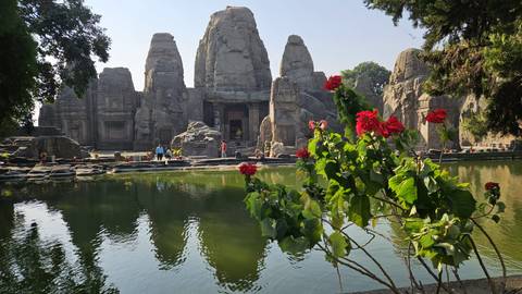       Historic stone temple reflected in a pond surrounded by greenery.
  