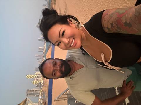 Two people posing with a city skyline in the background during blue hour.
