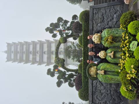 People in front of a pagoda and stone statues in misty weather.