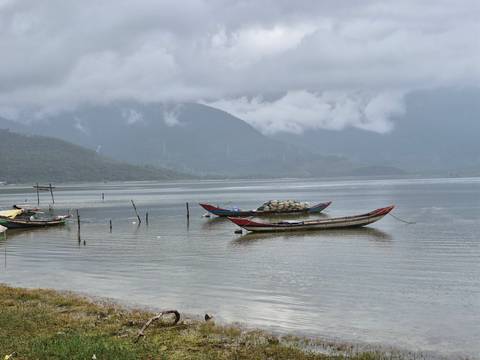       Boats anchored at a calm bay with mountains in the background.
  
