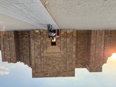       Visitors entering an ancient stone building under the sunset.
  