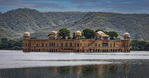       Jal Mahal, a palace located in the middle of a lake with surrounding hills.
  
